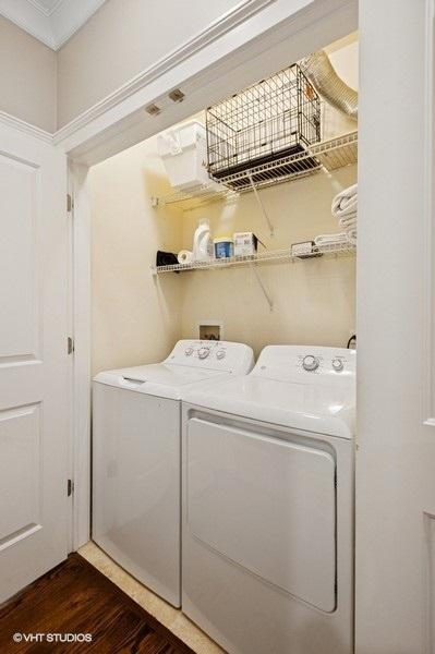 clothes washing area with dark wood-type flooring, laundry area, and washer and clothes dryer