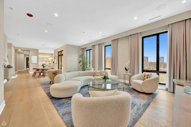living room with recessed lighting, light wood-style flooring, visible vents, and baseboards