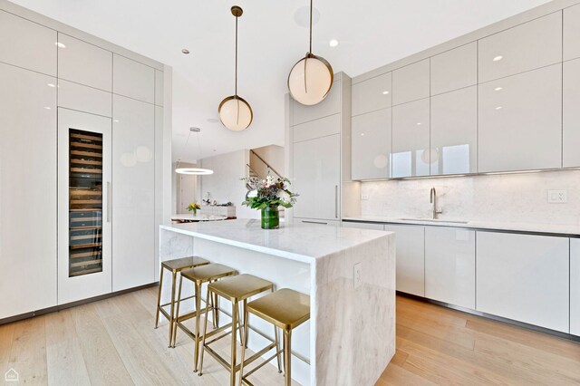 305 S Racine Ave Ph-A, Ph-A Chicago, IL 60607 - kitchen with modern cabinets, a sink, light wood-type flooring, and a kitchen breakfast bar