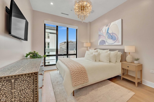 bedroom with visible vents, light wood finished floors, baseboards, and an inviting chandelier