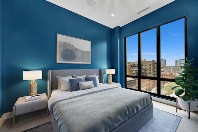 bedroom with a city view, visible vents, and carpet