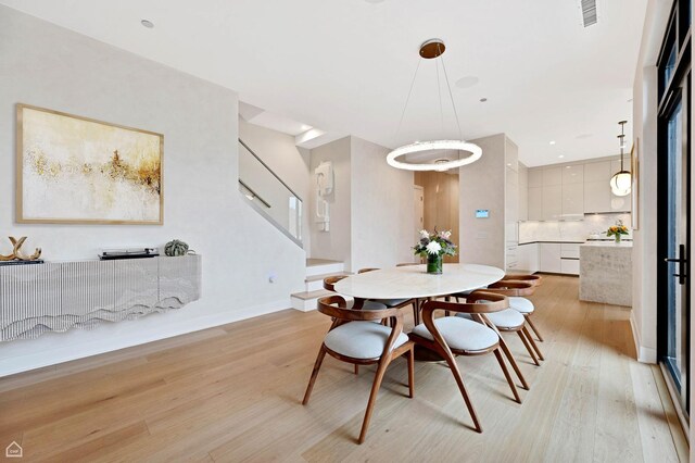 dining room featuring light wood-style floors, visible vents, and baseboards