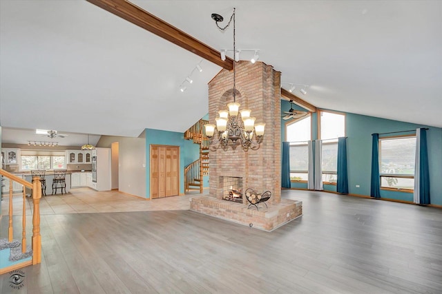 unfurnished living room with track lighting, high vaulted ceiling, wood finished floors, beamed ceiling, and stairway