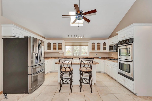 kitchen featuring stainless steel appliances, a ceiling fan, glass insert cabinets, and a center island