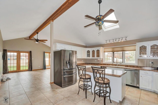 kitchen with a ceiling fan, a sink, lofted ceiling with skylight, a breakfast bar, and stainless steel appliances