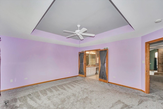 interior space featuring carpet flooring, a tray ceiling, and baseboards