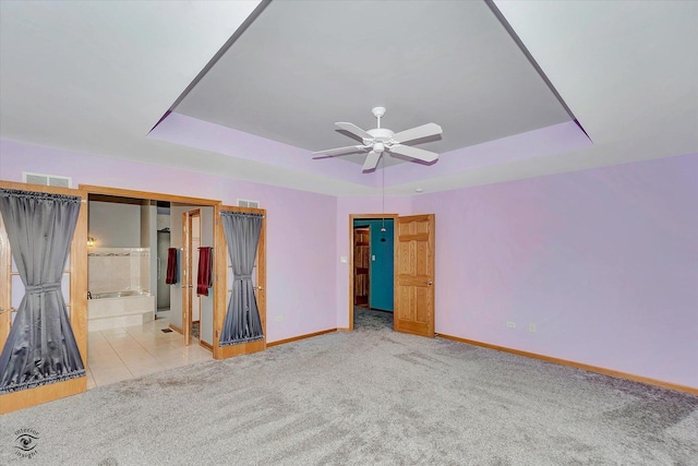 unfurnished bedroom with a raised ceiling, baseboards, carpet, and visible vents