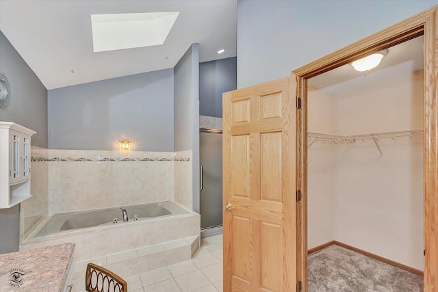 full bathroom with a garden tub, a skylight, tile patterned flooring, a stall shower, and a spacious closet