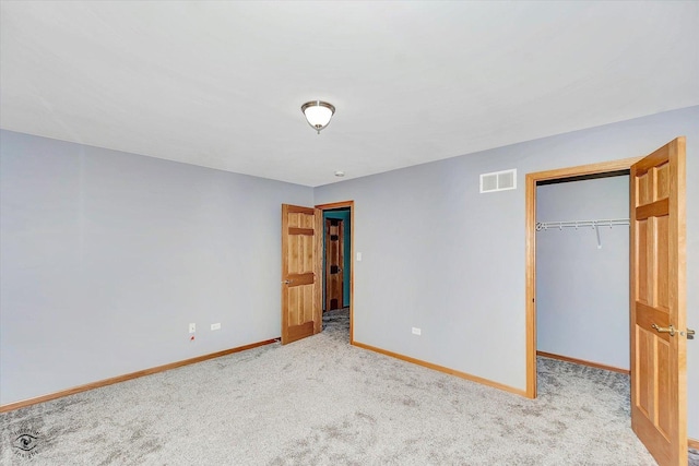 unfurnished bedroom with carpet flooring, a walk in closet, baseboards, visible vents, and a closet