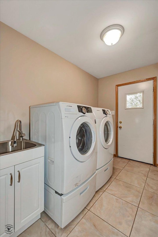 clothes washing area with a sink, light tile patterned floors, cabinet space, and washing machine and clothes dryer