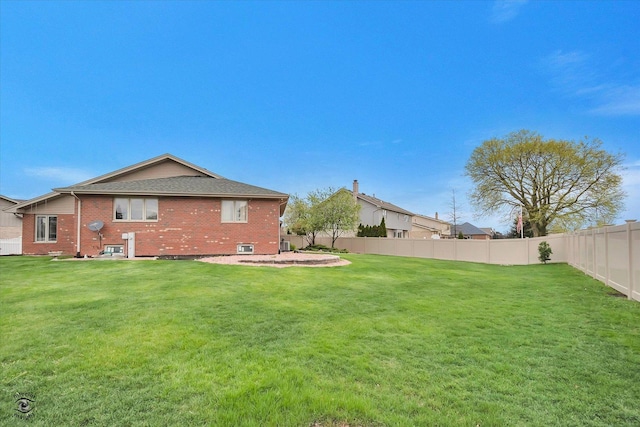 rear view of house with a yard, brick siding, and fence