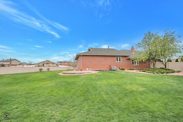rear view of house with a lawn, brick siding, fence, and a chimney