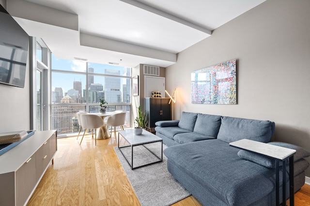 living area with visible vents, floor to ceiling windows, and light wood-style floors