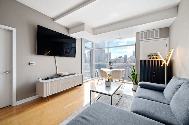 living area featuring light wood-type flooring, baseboards, floor to ceiling windows, and visible vents