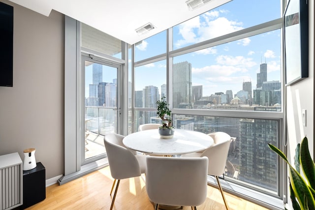 dining area featuring a view of city, wood finished floors, and visible vents