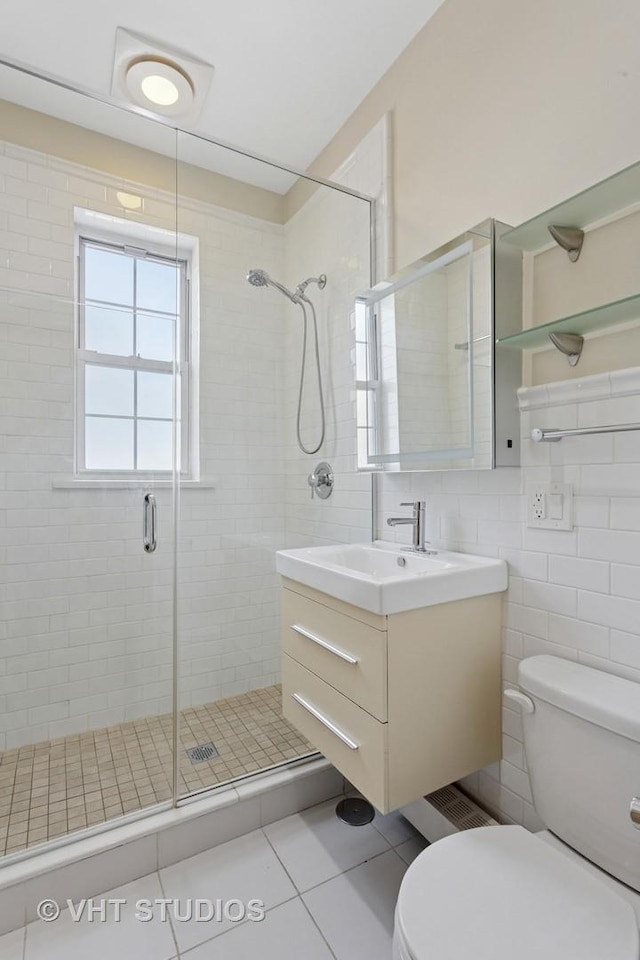 bathroom with tile patterned flooring, vanity, toilet, and a shower stall