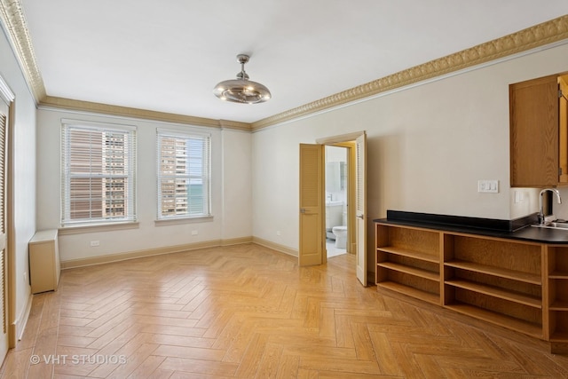 spare room featuring baseboards, ornamental molding, and a sink