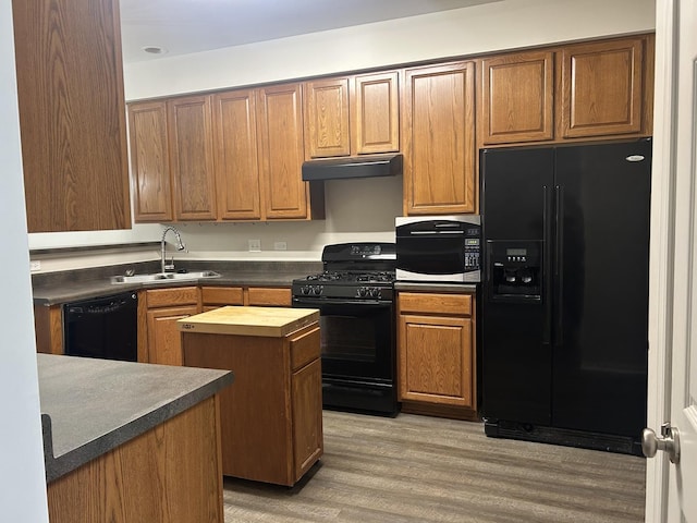 567 S Jade Ln, Round Lake, IL 60073 - kitchen with a center island, under cabinet range hood, a sink, light wood-style flooring, and black appliances