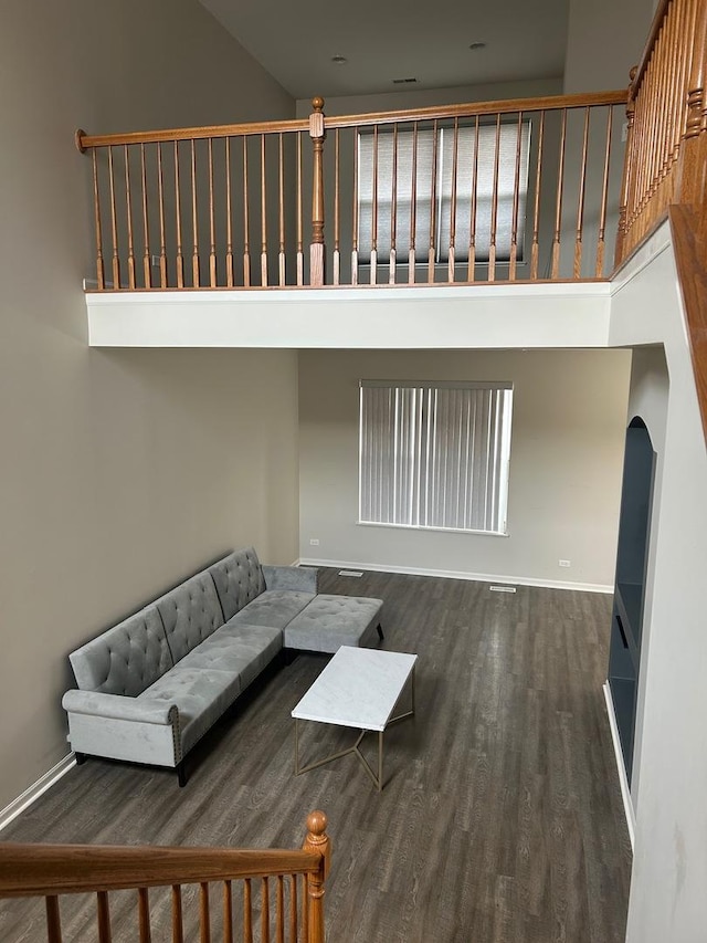 567 S Jade Ln, Round Lake, IL 60073 - unfurnished living room featuring arched walkways, baseboards, wood finished floors, and a towering ceiling