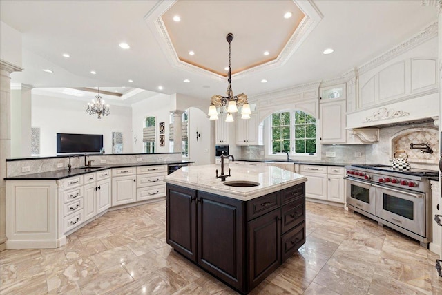 kitchen with range with two ovens, a notable chandelier, a tray ceiling, and ornate columns