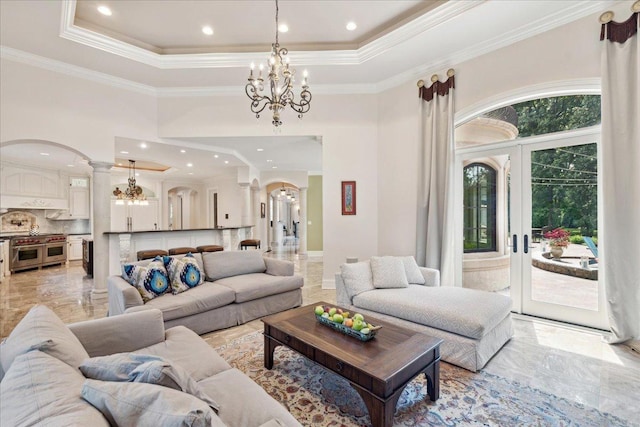 living area featuring marble finish floor, ornate columns, a tray ceiling, ornamental molding, and arched walkways