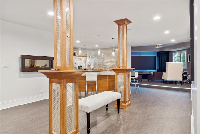 bar with recessed lighting, wet bar, wood finished floors, and baseboards