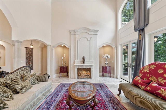 living room featuring a high ceiling, arched walkways, marble finish floor, and ornate columns