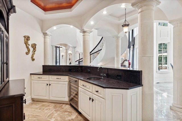 bathroom featuring a tray ceiling, recessed lighting, ornate columns, marble finish floor, and beverage cooler