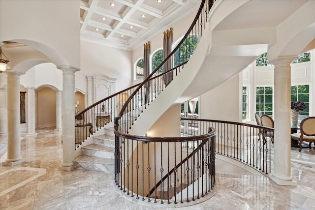 stairway with marble finish floor, beam ceiling, a towering ceiling, and coffered ceiling