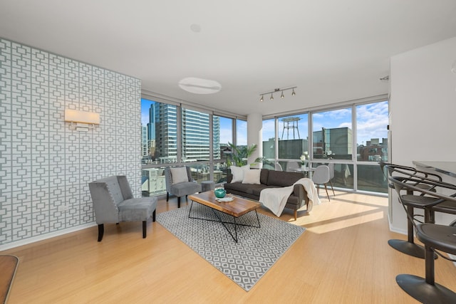 living area with track lighting, a view of city, wood finished floors, and floor to ceiling windows
