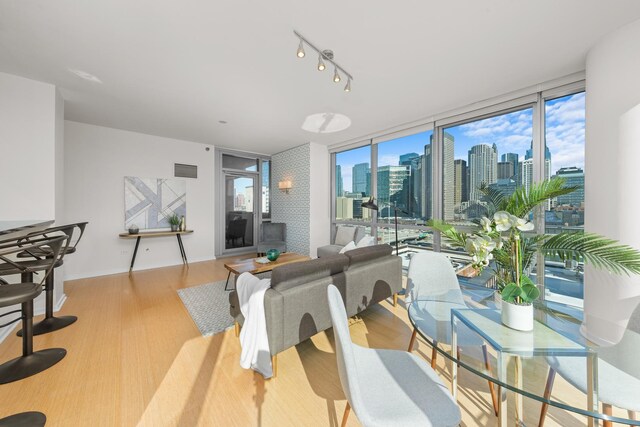 dining space with a city view, a healthy amount of sunlight, wood finished floors, and floor to ceiling windows
