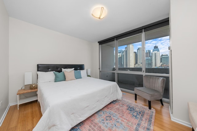 bedroom featuring baseboards, wood finished floors, and a view of city