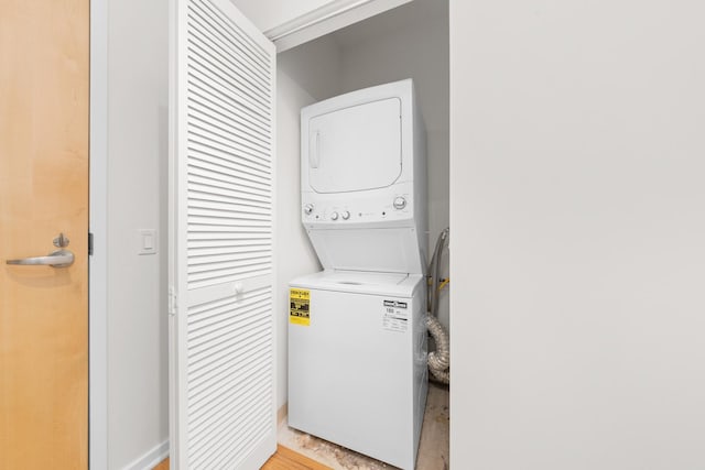 washroom with stacked washer and clothes dryer, laundry area, and light wood-type flooring