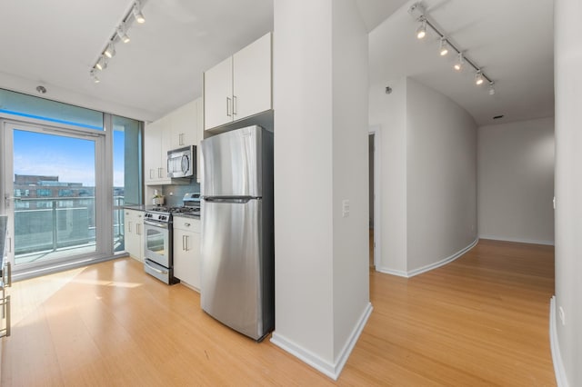 kitchen with track lighting, dark countertops, stainless steel appliances, and light wood-style floors