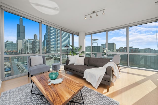 sunroom featuring expansive windows, wood finished floors, a healthy amount of sunlight, and a view of city