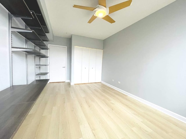 unfurnished living room with ceiling fan, light wood-style floors, and baseboards