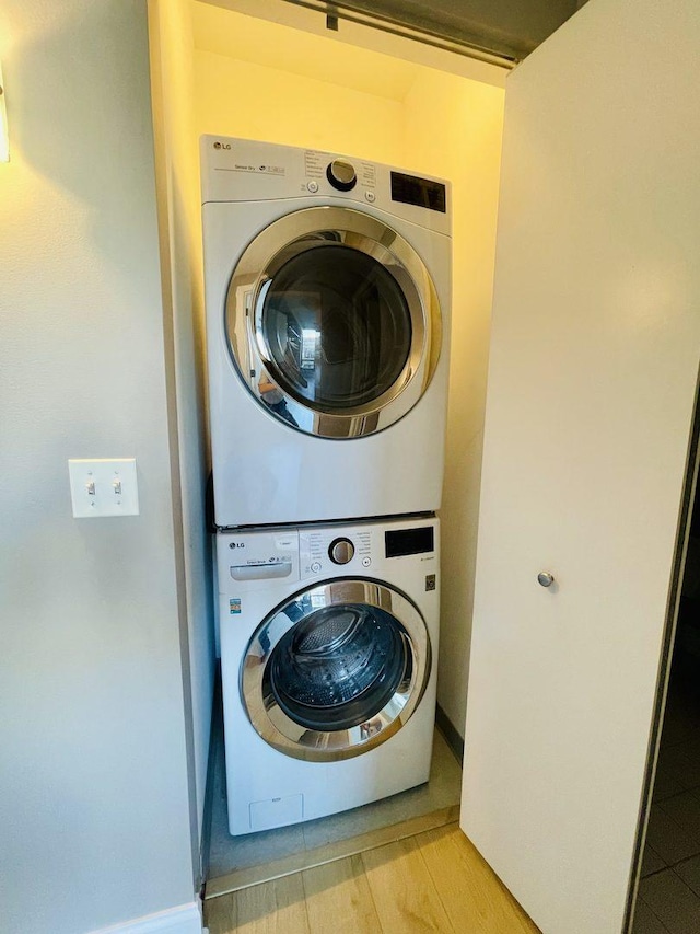 laundry area with estacked washer and dryer and baseboards