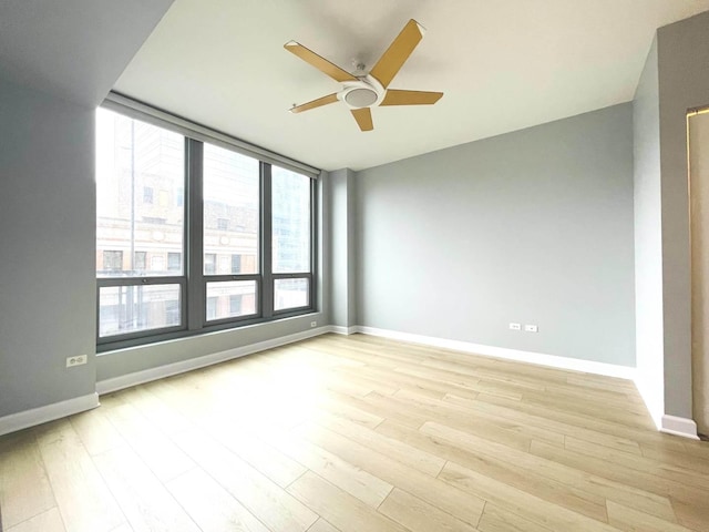 spare room featuring light wood finished floors, baseboards, and ceiling fan