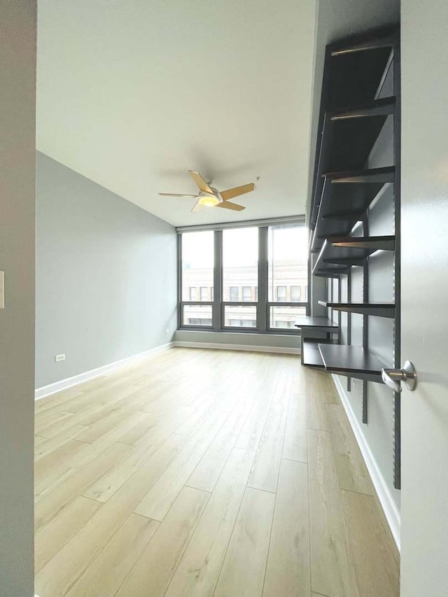 unfurnished room featuring a ceiling fan, wood finished floors, and baseboards