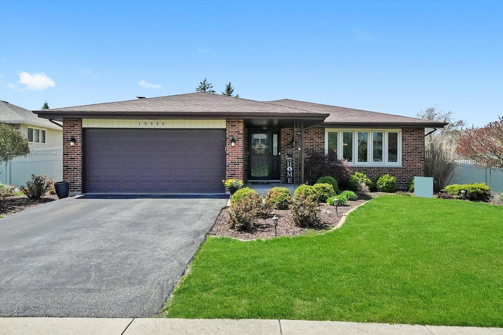 view of front of property featuring a front lawn, driveway, a garage, and brick siding