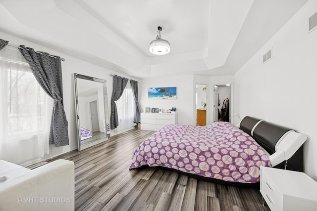 bedroom featuring a raised ceiling, visible vents, and wood finished floors