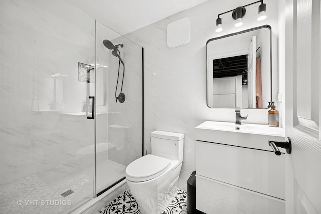 bathroom with a stall shower, vanity, toilet, and tile walls