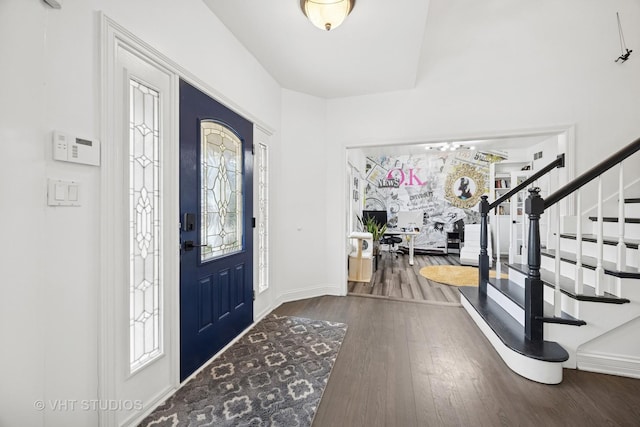 foyer featuring stairway, wood finished floors, baseboards, and a healthy amount of sunlight