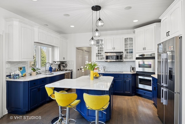 kitchen with stainless steel appliances, blue cabinets, dark wood-style floors, and a sink