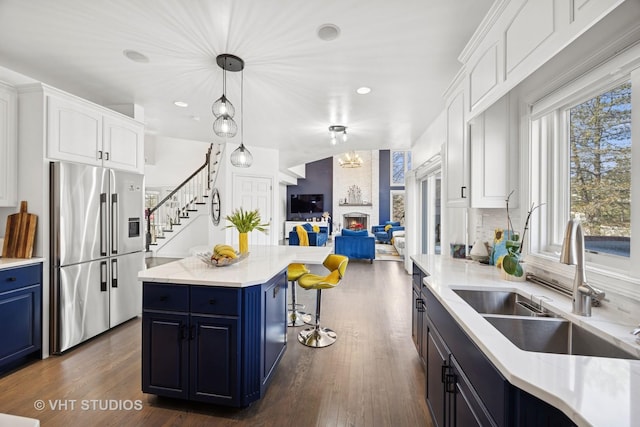 kitchen with a sink, open floor plan, stainless steel fridge, and blue cabinetry