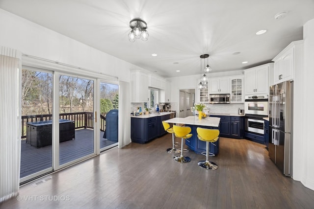 kitchen featuring stainless steel appliances, a kitchen bar, white cabinetry, a kitchen island, and light countertops