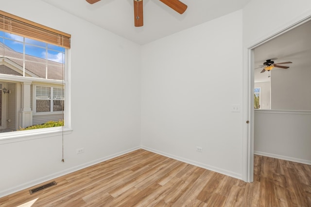 empty room with ceiling fan, light wood-style floors, a wealth of natural light, and visible vents