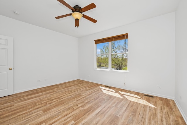 spare room with visible vents, a ceiling fan, light wood-style flooring, and baseboards