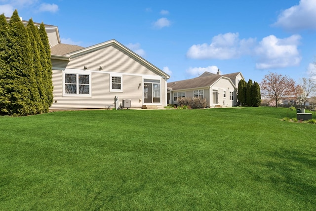 back of house featuring central AC, entry steps, and a lawn