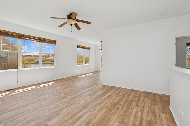 empty room featuring baseboards, a ceiling fan, and light wood-style floors